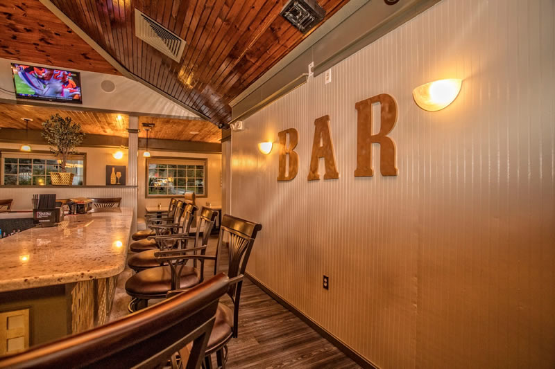 Bar area with high stools beneath a large BAR sign