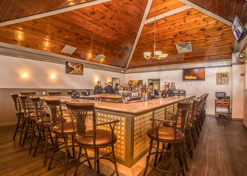 L-shaped bar with seating and wall-mounted televisions