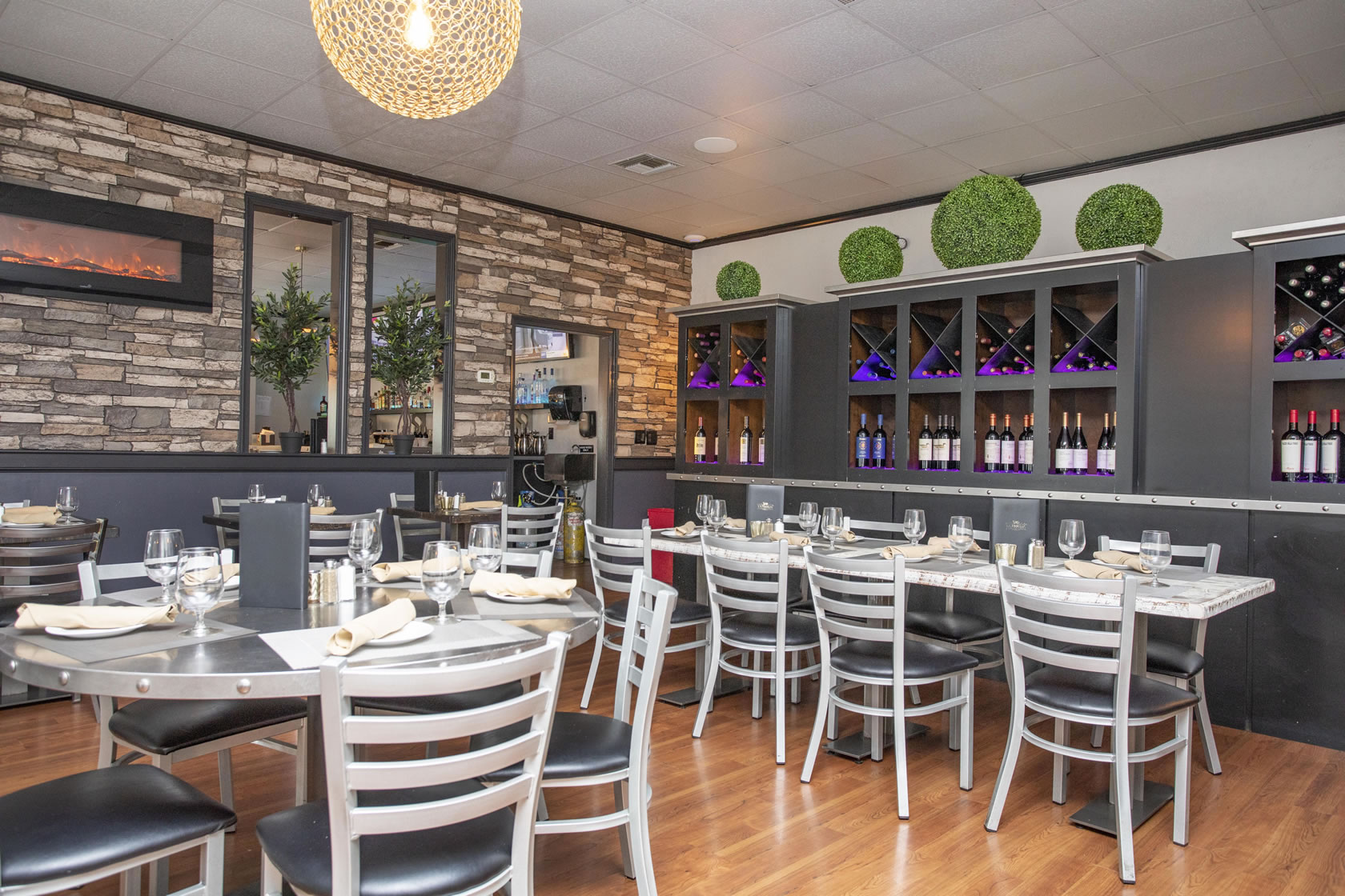 Dining room set with white linens and floor-to-ceiling wine racks