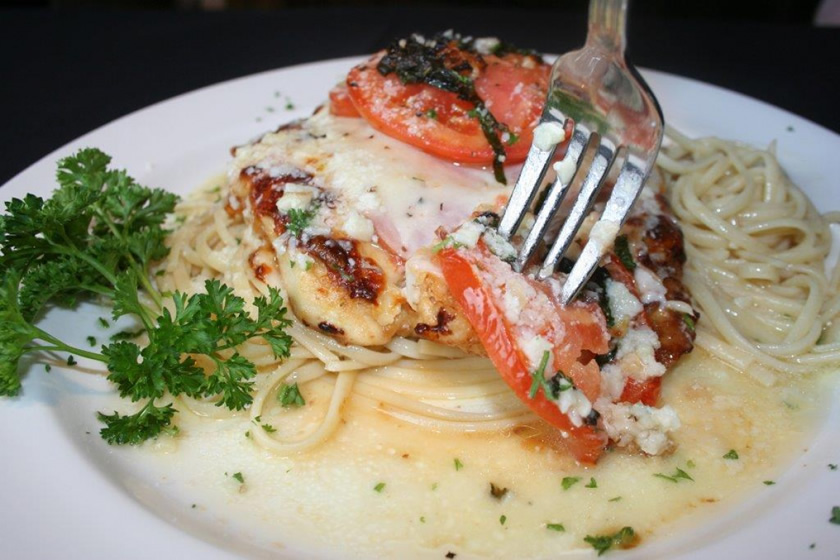 Chicken parmesan over pasta with a fork lifting a piece