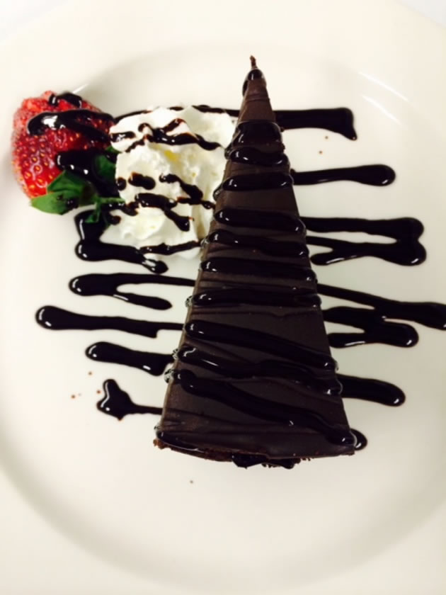 Five-layer chocolate cake with whipped cream, strawberry and chocolate drizzle