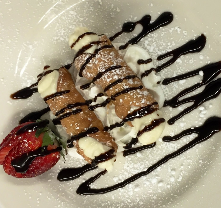Two traditional cannoli with whipped cream and a strawberry