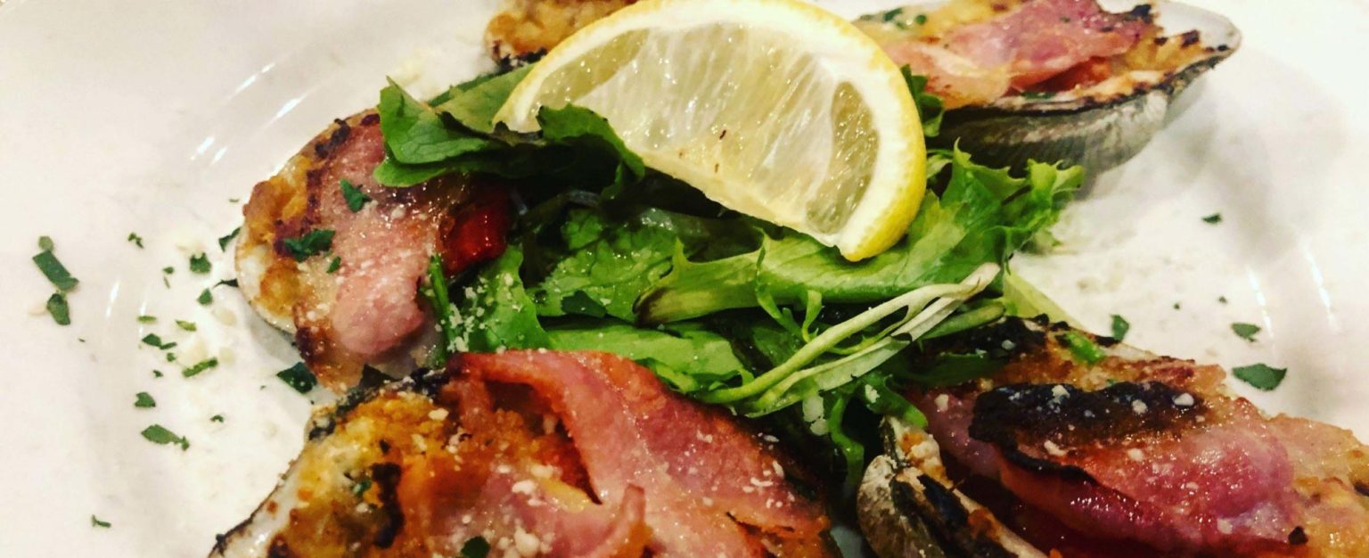 Baked stuffed clams topped with bacon and a lemon wedge